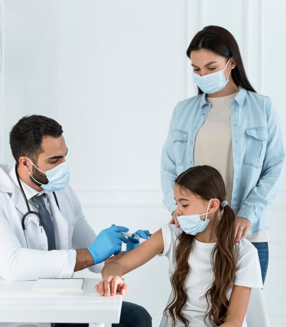 A doctor giving a young girl a vaccine while her mother watches